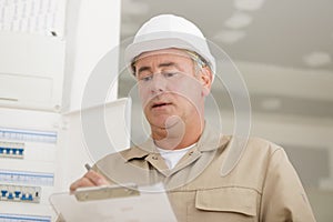 Portrait electrician standing next to fuseboard