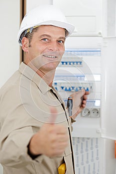 Portrait electrician standing next to fuseboard