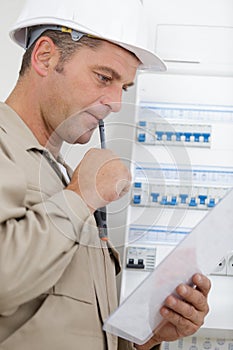 Portrait electrician standing next to fuseboard