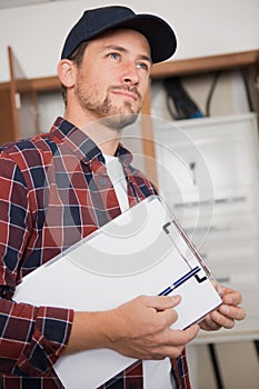 portrait electrician standing next to fuseboard