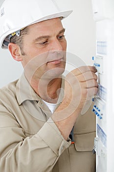 portrait electrician standing next to fuseboard