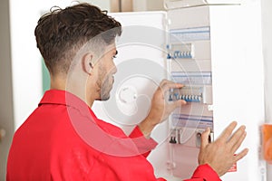 portrait electrician standing next to fuseboard