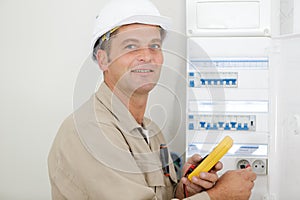 portrait electrician standing next to fuseboard