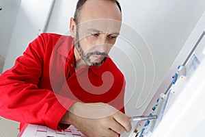 portrait electrician standing next to fuseboard