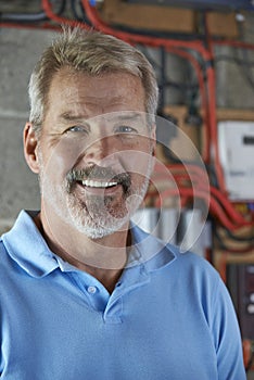 Portrait Of Electrician Standing Next To Fuseboard