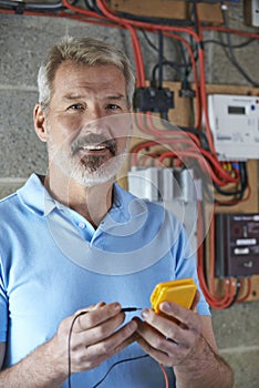 Portrait Of Electrician Standing Next To Fuseboard