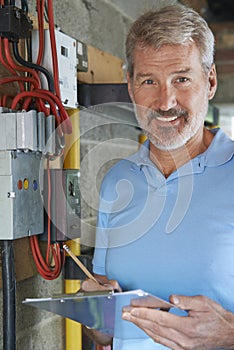 Portrait Of Electrician Standing Next To Fuseboard