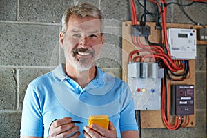 Portrait Of Electrician Standing Next To Fuseboard