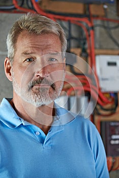 Portrait Of Electrician Standing Next To Fuseboard