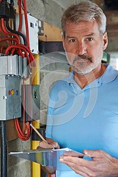 Portrait Of Electrician Standing Next To Fuseboard