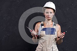 Portrait of electrician woman in uniform and white helmet holds in hand wire-cutters and nippers. Female worker in workwear