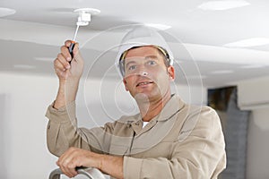 Portrait electrician working on light fitting