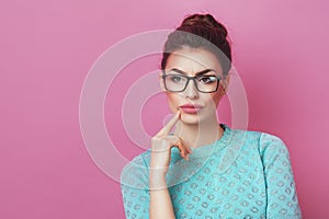 Portrait of elegance thoughtful woman having hair bun in bright skirt isolated on pink background touching chin and have a great i