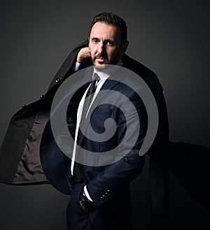 Portrait of elegant bearded businessman, boss in stylish modern office suit leaving room holding his coat on shoulder