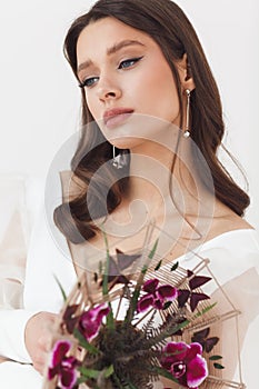 Portrait of elegant beautiful bride with unusual bouquet of flowers. Perfect makeup and hairstyle