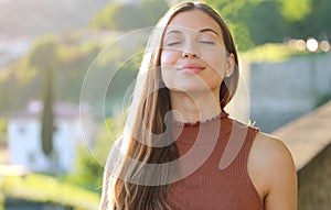 Portrait of elegant dreamy woman with closed eyes breathes outdoors on sunset