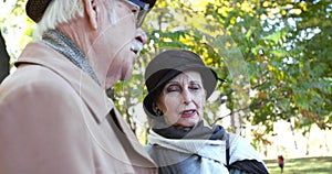 Portrait of elegant, elderly married couple talking during a walk in autumn park