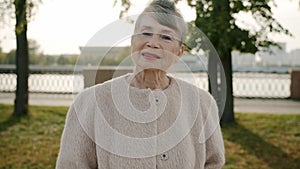Portrait of elegant elderly woman smiling looking at camera outdoors in modern city street