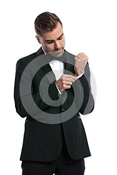 Portrait of elegant fashion man in tuxedo adjusting sleeve