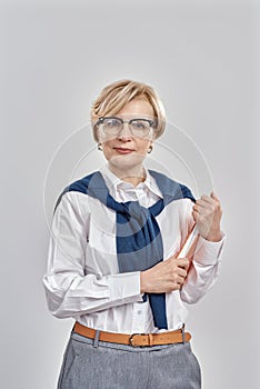 Portrait of elegant middle aged caucasian woman wearing business attire and glasses looking at camera, holding her