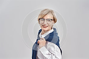 Portrait of elegant middle aged caucasian woman wearing business attire and glasses smiling at camera while posing