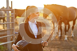 Rider woman with whip at the sunset