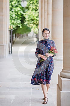 Portrait of elegant woman in a blue dress posing next to a city building