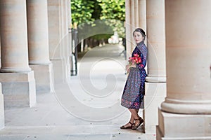 Portrait of elegant woman in a blue dress posing next to a city building