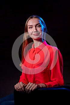 Portrait of elegant woman with long hair in red dress and dark background. Model posing doring studio photo shot