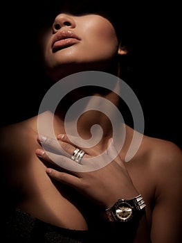 Portrait of an elegant woman with luxury wide rings made from precious metals on her finger and watch on wrist