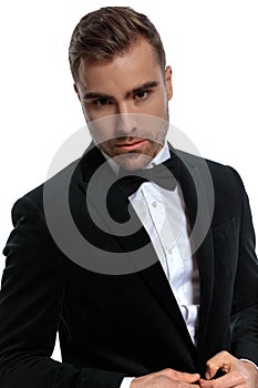 Portrait of elegant young man buttoning black tuxedo