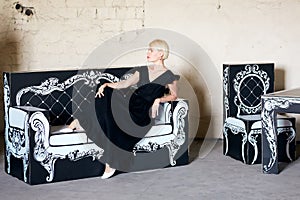 Portrait of an elegantly beautiful young woman posing on an cardboard antique couch.