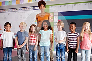 Portrait Of Elementary School Pupils Standing In Classroom With Female Teacher