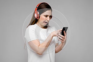 Portrait of emotional beautiful happy plus size model in headphones looking in mobile phone listening to music