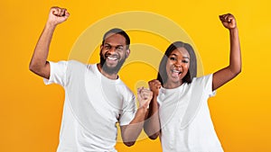 Portrait of emotional black couple celebrating win with raised fists