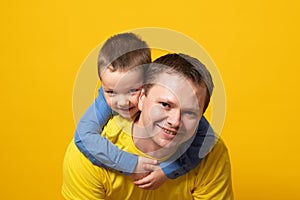 Portrait of emotional father and his son on yellow background