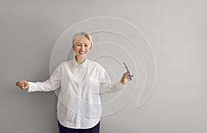 Portrait of emotional, happy, joyful and stylish senior woman against gray wall.