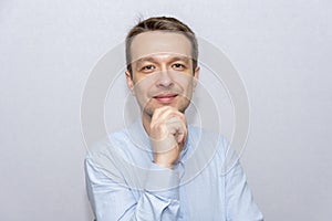 Portrait of an emotional man 30-35 years old in a light shirt, looking into the camera, on an isolated gray background.