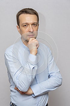 Portrait of an emotional man 30-35 years old in a light shirt, looking into the camera, on an isolated gray background.