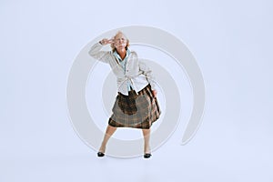 Portrait of emotional senior woman in retro style clothes, vintage outfit dancing rock-and-roll isolated on white