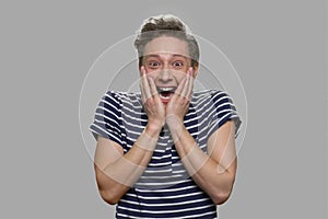 Portrait of emotional teen boy on gray background.