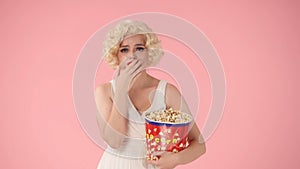 Portrait of an emotional woman crying with a big bucket of popcorn close up. Woman in the image of Marilyn Monroe crying