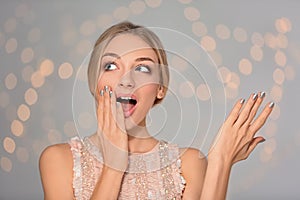 Portrait of emotional young woman with shiny manicure on blurred background