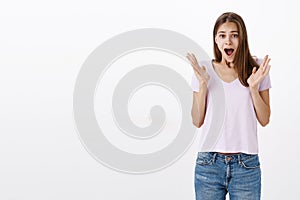Portrait of emotive pretty young european female student in casual t-shirt yelling from amazement and joy raising and