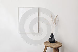 Portrait empty picture frame mockup in sunlight. Dry festuca, bunny tail grass in modern black organic shaped vase