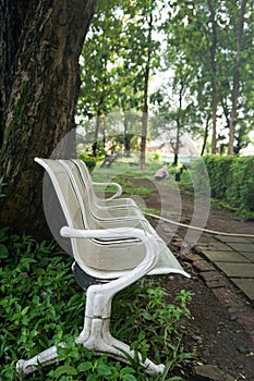 portrait of empty rusty white park bench in park