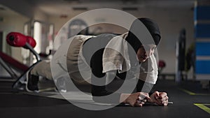 Portrait of endurant Middle Eastern sportswoman in plank position on exercise mat indoors. Concentrated motivated