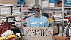 Portrait of energetic multiracial man looking at the camera and smiling while holding banner with donation word in