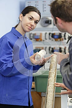 Portrait engineer and apprentice examining component in factory