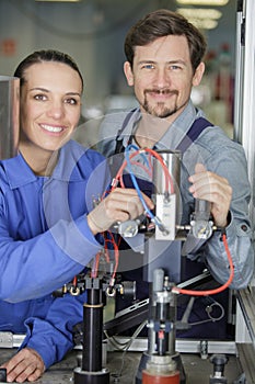 portrait engineer and apprentice examining component in factory